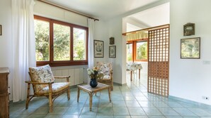 A room with a large window, a chair, a table, and a decorative screen. - Villa Luia by MMega Villas  (Marina di Pietrasanta)