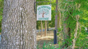 Een bordje voor Shearwood Cottage, gelegen in een bebost gebied.