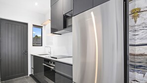 Una cocina moderna con un refrigerador de acero inoxidable, armarios oscuros y un ventanal con vistas al exterior.