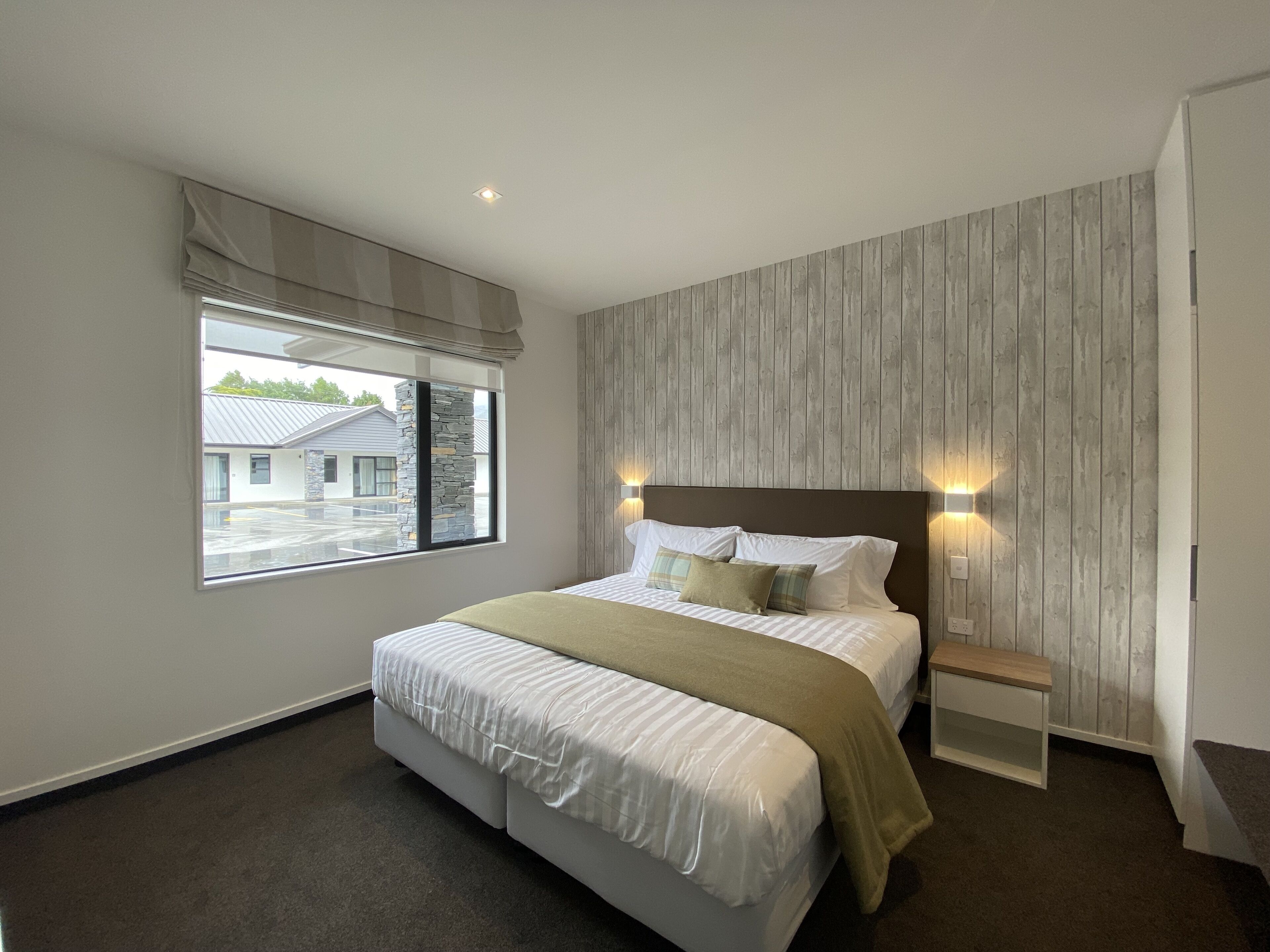 Una camera da letto moderna con un letto grande, una parete decorata in pietra e vista su un parcheggio.