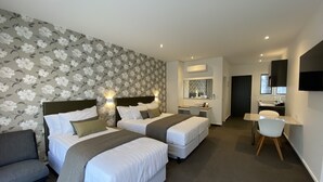 Una habitación de hotel moderna con dos camas, un escritorio, una silla y un espejo grande.