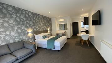 A hotel room with a bed, a sofa, a desk, and a TV.