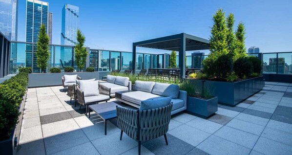 A rooftop terrace with outdoor seating, a pergola, and city views.