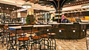 A bar area with round tables, bar stools, and a bartender.