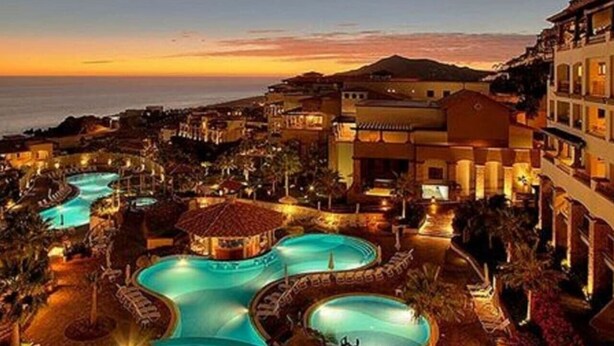 A resort with multiple swimming pools, a central gazebo, and buildings with balconies.