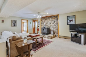 A cozy living room with a stone fireplace, a television, and a ski patrol sign.