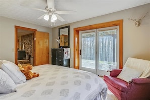 A bedroom with a bed, a chair, a dresser, a mirror, and a ceiling fan.
