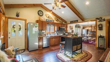 A spacious kitchen with wooden cabinets, a central island, and a dining area with a chandelier.