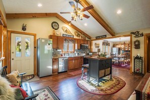 A spacious kitchen with wooden cabinets, a central island, and a dining area with a chandelier.