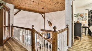 A wooden staircase with a white railing, a mounted deer head, and a view into a room with a bicycle and a plant.