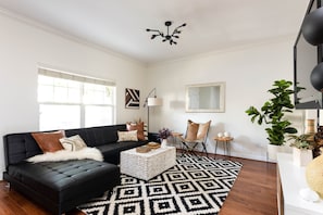 A modern living room with a black sofa, a patterned rug, and a coffee table.