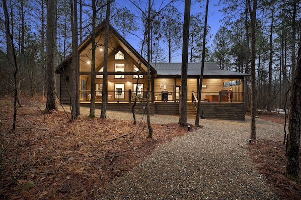 Relax on the spacious front porch surrounded by tall trees in a secluded forest setting.