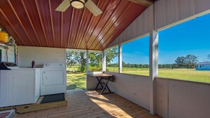 Ein überdachter Außenbereich mit Waschmaschine, Tisch und Deckenventilator.