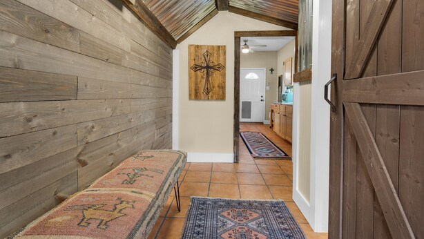 Ein Korridor mit Holzwänden, einer Bank, einem gemusterten Teppich und einem Kruzifix an der Wand.