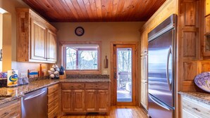 A kitchen with wooden cabinets, a stainless steel refrigerator, and a granite countertop.