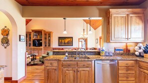 A kitchen with wooden cabinets, granite countertops, a stainless steel dishwasher, and pendant lighting.