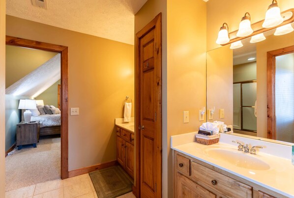 Un baño con un espejo grande, armarios de madera, un lavabo y un perchero para toallas.