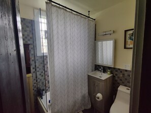 Un baño con cortina de ducha, lavamanos, inodoro y espejo.
