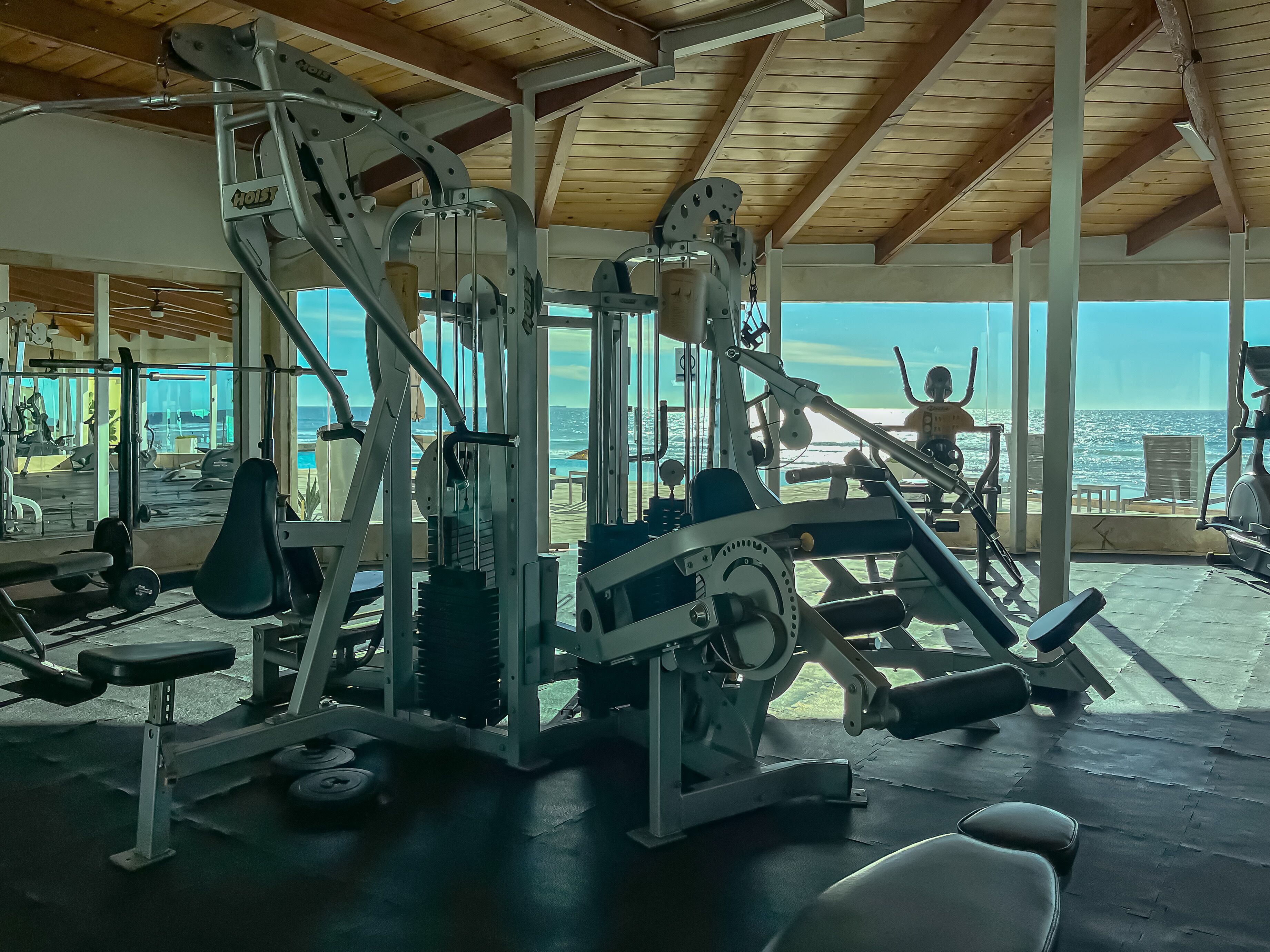 A gym with various exercise equipment and a view of the ocean.
