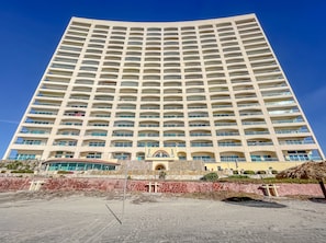 A tall, rectangular hotel with multiple balconies and a central entrance.