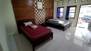 Una habitación de hotel con dos camas, piso de baldosas, pared de ladrillo y una ventana con cortinas.