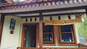 Un edificio tradicional con techo de tejas, vigas de madera y un cartel que dice "Homestay Marsudi".