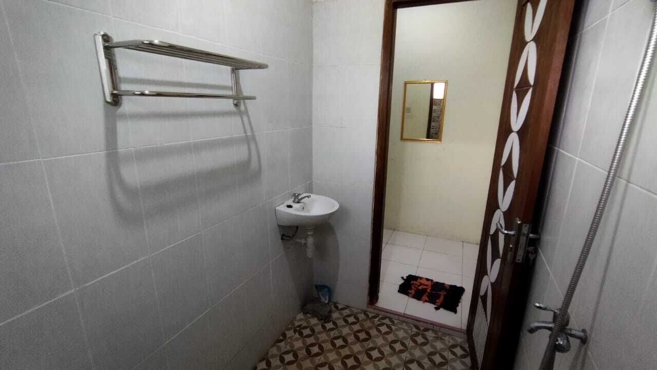 Un bany petit amb un rentapelats blanc, un suport per tovalloles i una dutxera.