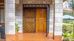 A wooden door with a metal grid, a potted plant, and a tiled entrance. - 2 Bed Cottage Sleeps 4 - Onsite Parking, Garden (Nairobi)