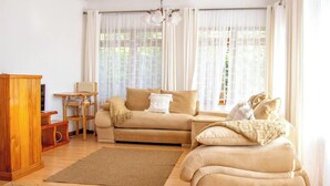 A cozy living room with a sofa, a coffee table, a wooden cabinet, and a rug. - 2 Bed Cottage Sleeps 4 - Onsite Parking, Garden (Nairobi)
