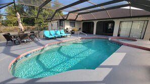 A swimming pool with a covered patio area, including lounge chairs and a table.