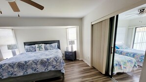 Ein Schlafzimmer mit einem Bett, einem Nachttisch, einem Spiegel und einem Deckenventilator.