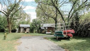 A gravel path leading to rustic cabins surrounded by trees. - Nature's Tiny Riverside Hideaway (Fayetteville)