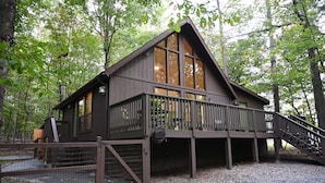 Een chalet met een houten terras, een trap en een omheind gebied.