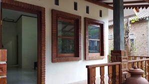 A building with two windows, a wooden railing, and a brick wall. - Borobudur Kampung Homestay - Sumaedi (Magelang)