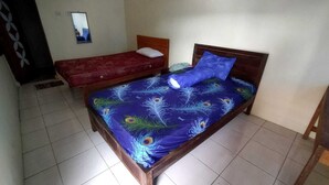A room with two beds, one with a red bedspread and the other with a blue bedspread featuring peacock feather patterns. - Borobudur Kampung Homestay - Sumaedi (Magelang)