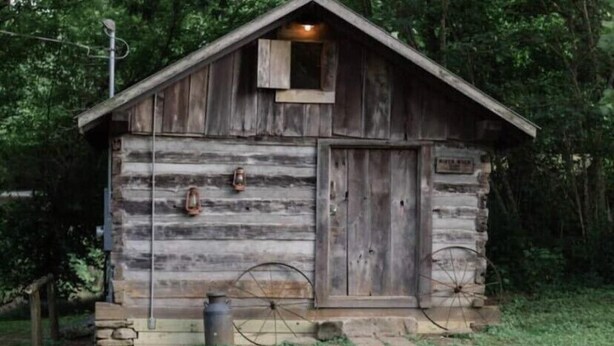 A rustic wooden cabin with a sloped roof, a small window, and a door. - Elk Riverside Escape (Fayetteville)