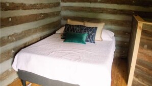 A single bed with a white bedspread and two pillows in a log cabin room. - Elk Riverside Escape (Fayetteville)