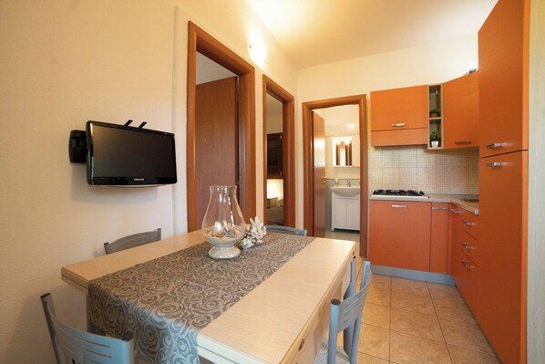 A dining area with a table, chairs, and a TV mounted on the wall.