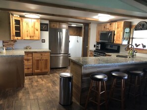 A kitchen with wooden cabinets, a stainless steel refrigerator, a microwave, and a granite countertop. - Luna’s Ranch  (Clewiston)
