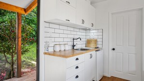 Une cuisine de taille réduite avec des meubles blancs, un plan de travail en bois, un évier et une planche à découper en bois.