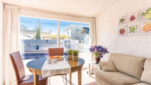 A cozy living area with a round table, a sofa, and a balcony with a view of buildings and a pool. - Vacation home Peni by Interhome (Empuriabrava)