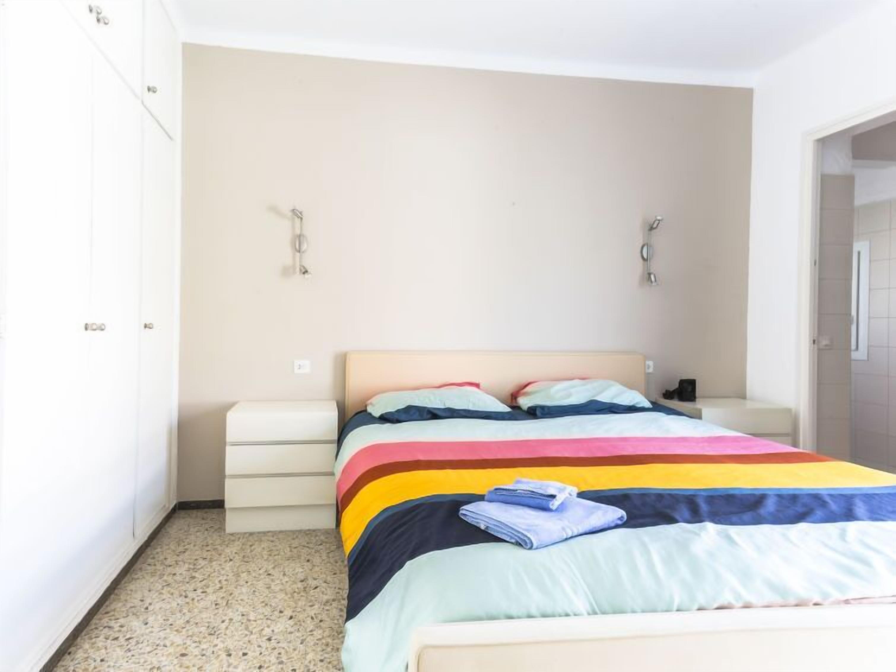 A bedroom with a bed, a nightstand, and a wardrobe.