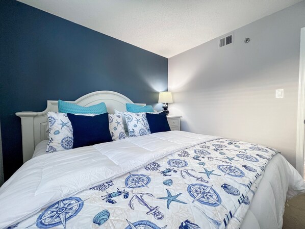 A bedroom with a bed, a nightstand, and a lamp.