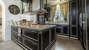 A modern kitchen with a central island, black cabinetry, and a large clock on the wall.