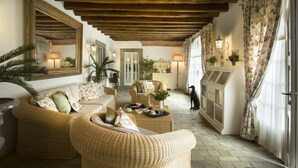 A cozy, well-lit room with wicker furniture, a fireplace, and floral curtains.