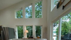 Una sala de estar moderna con un sofá modular, una mesa de centro redonda y ventanas amplias que ofrecen vistas a la vegetación exterior.
