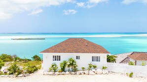 A white building with a tiled roof overlooking a beach and turquoise waters. - Ultimate Vacation in Paradise at BLU (Rolletown)