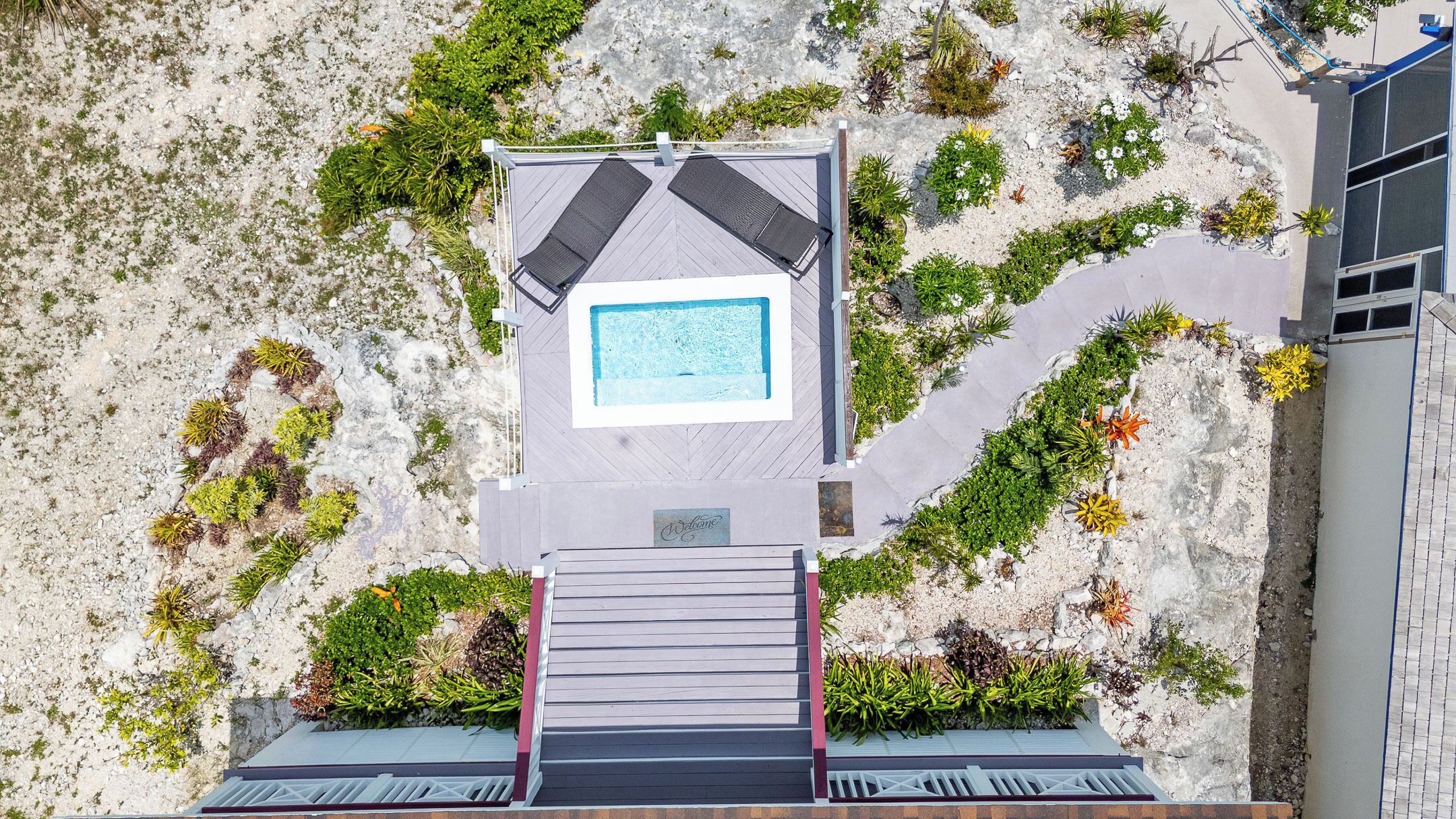 A rooftop pool with a view of the surrounding landscape, a staircase leading up to the pool, and a sign that reads "Welcome".