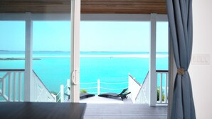 A balcony with a view of the ocean and a distant island. - Ultimate Vacation in Paradise at BLU (Rolletown)