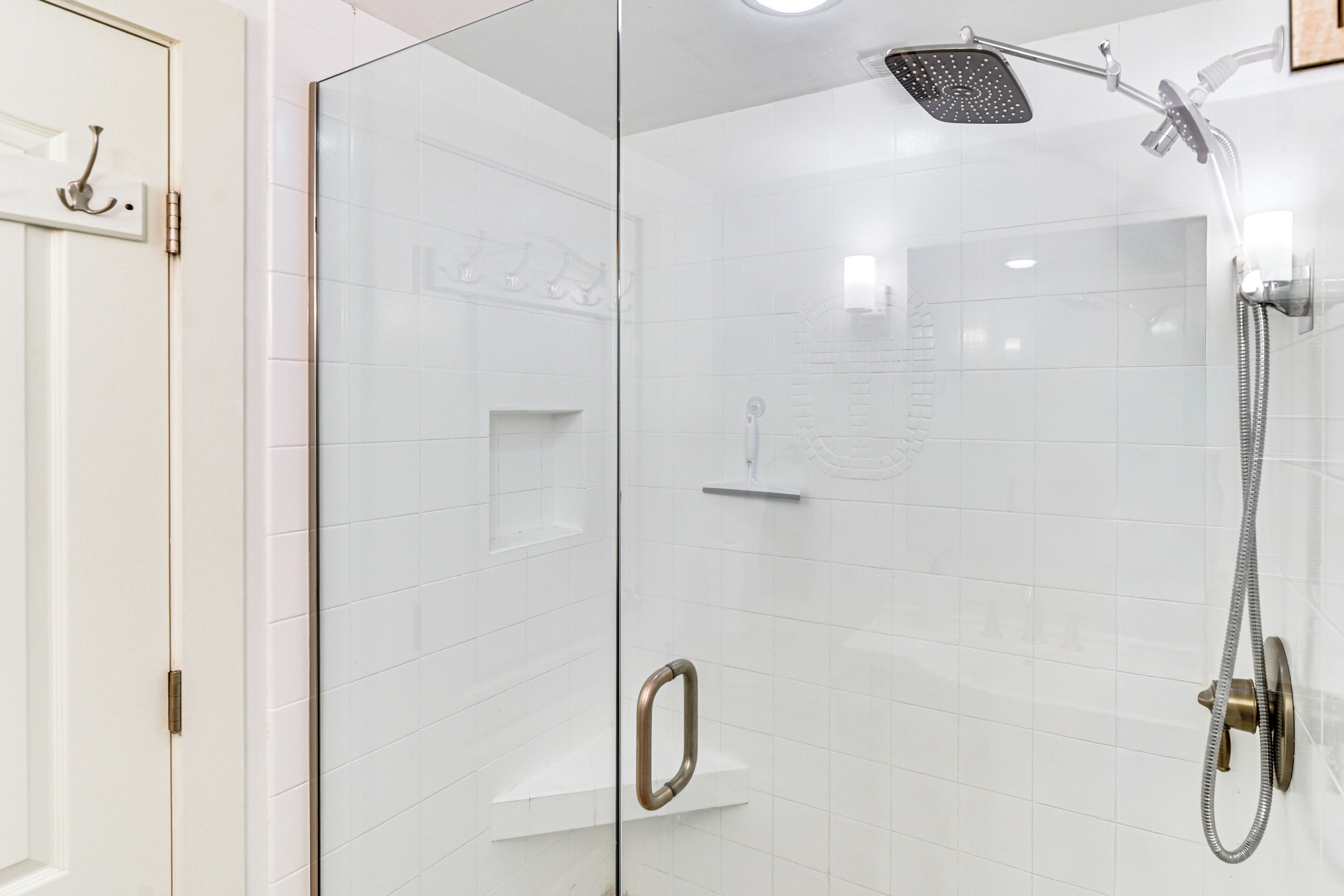 A modern bathroom with a glass shower enclosure, a handheld showerhead, and a handheld faucet.